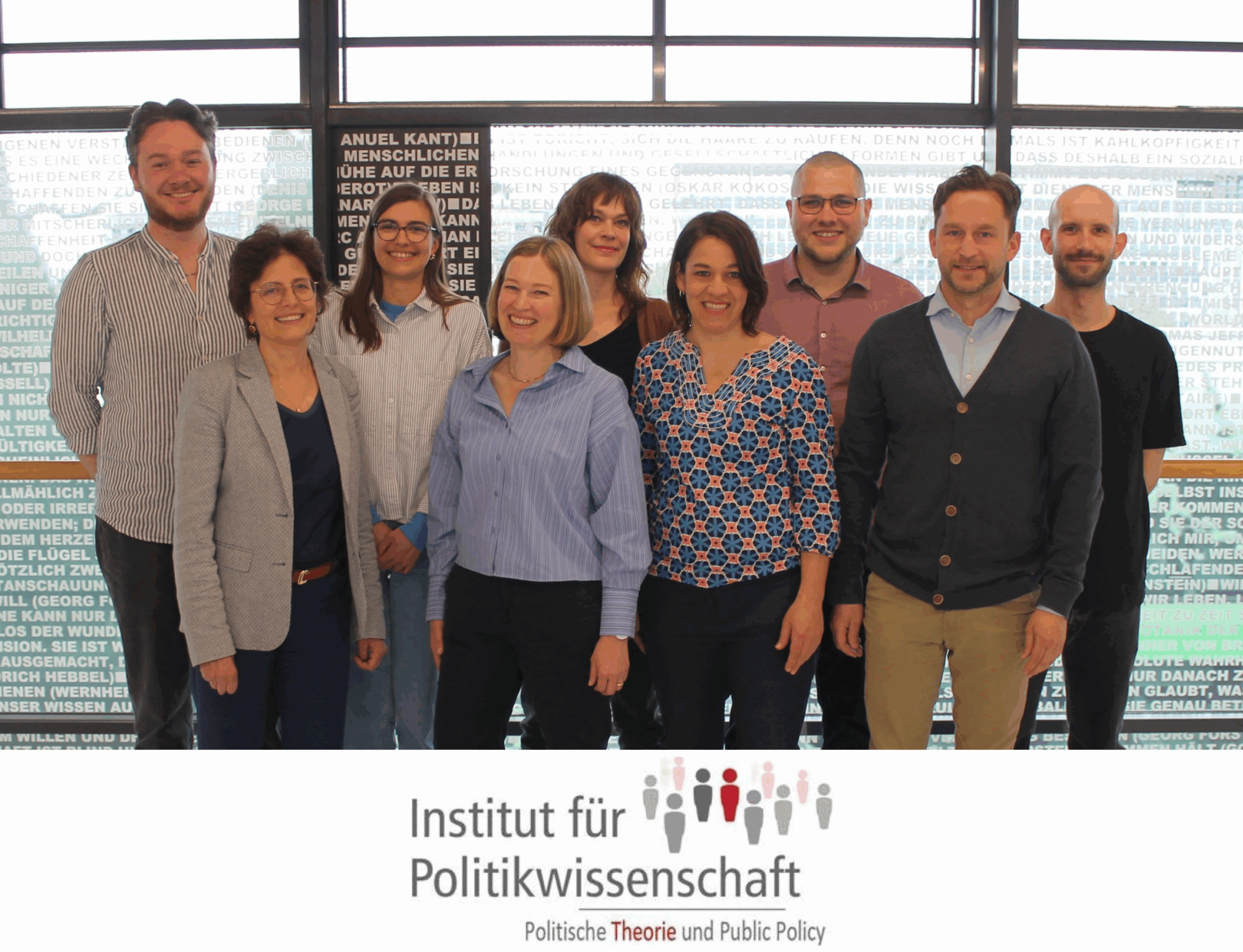 Ein Gruppenfoto des Bereichs Politische Theorie und Public Policy, auf dem die neun Mitglieder vor einem hellen Hintergrund stehen. Unten ist ein Banner mit dem Bereichslogo abgebildet.